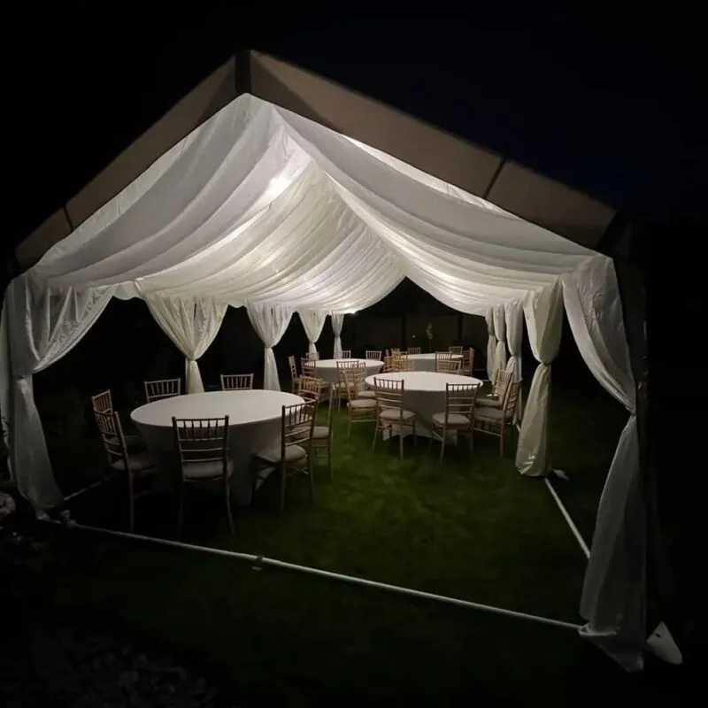 Evening wedding marquee with ivory draping, round tables and soft interior lighting