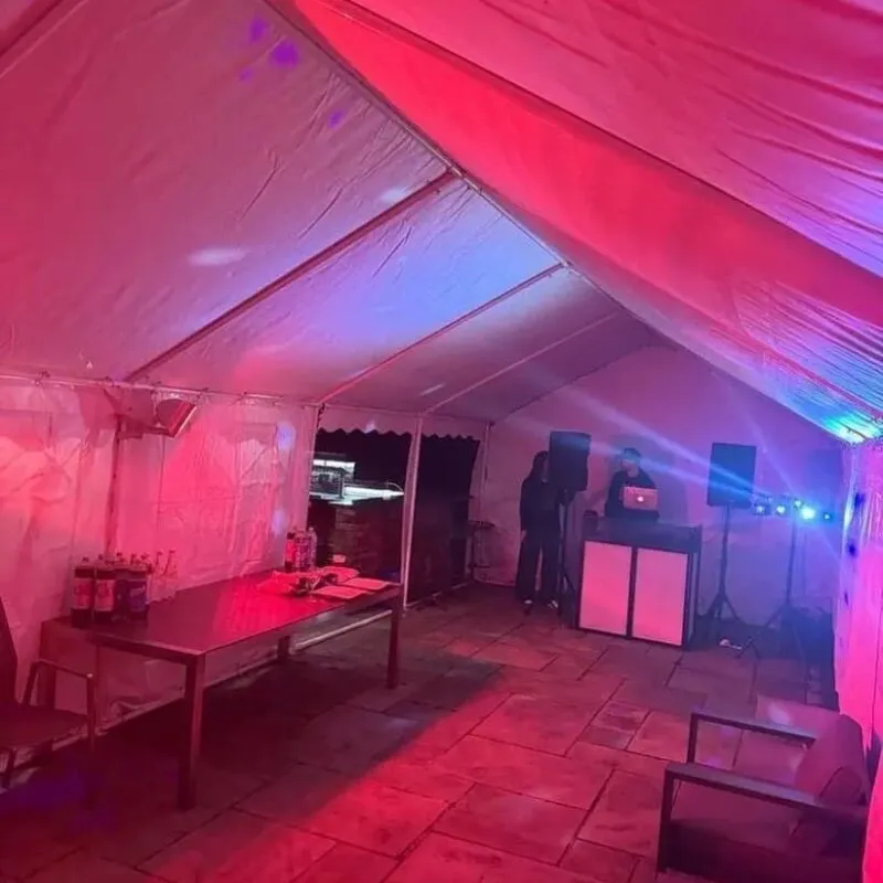 Party marquee with DJ booth, coloured lighting and drinks table setup