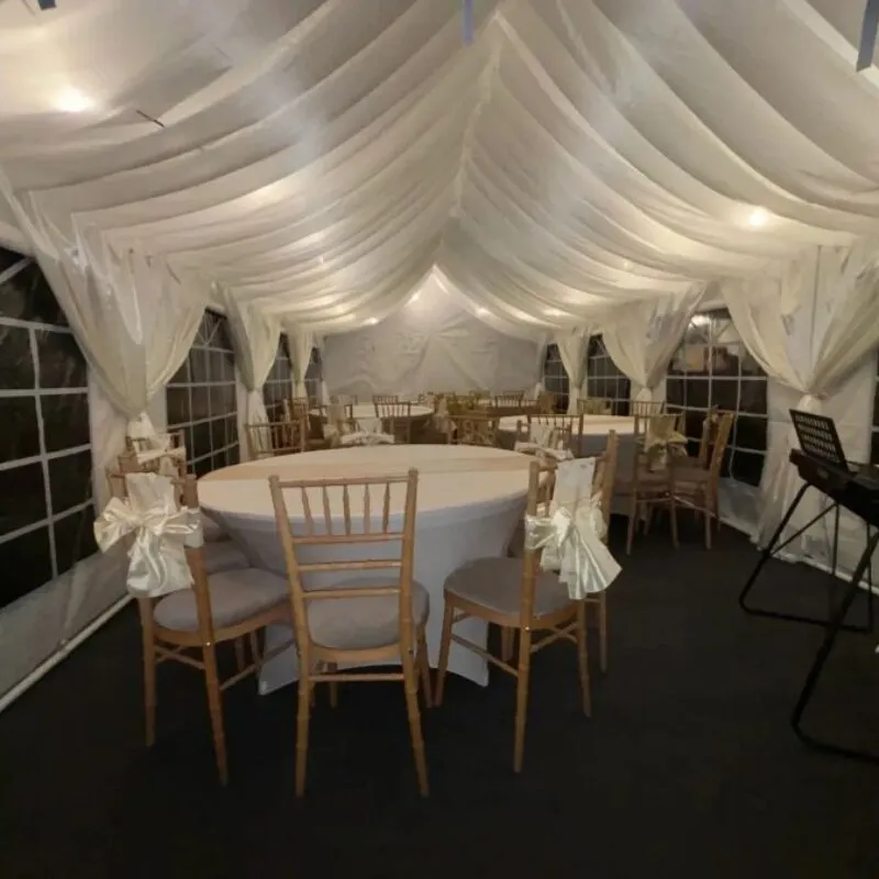 Ivory draped wedding marquee with round tables and chiavari chairs with chair sashes