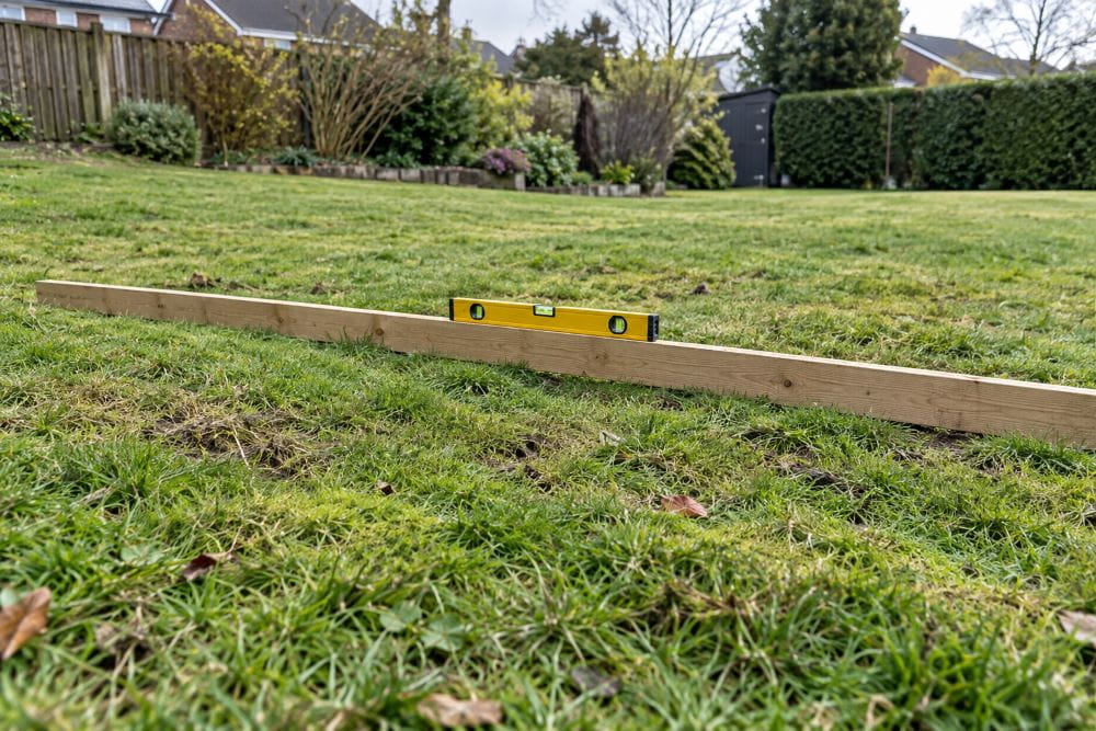 Checking uneven grass with a straight edge and spirit level before marquee installation