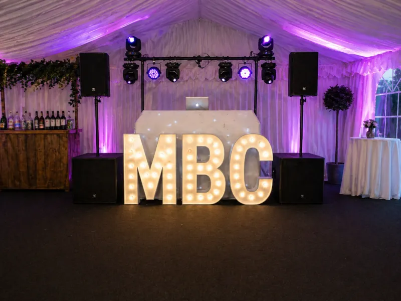 DJ Hire Essex – Marquee DJ Setup with Dancefloor and Lighting DJ hire setup in Essex marquee with speakers, lighting, illuminated letters and dancefloor for party event