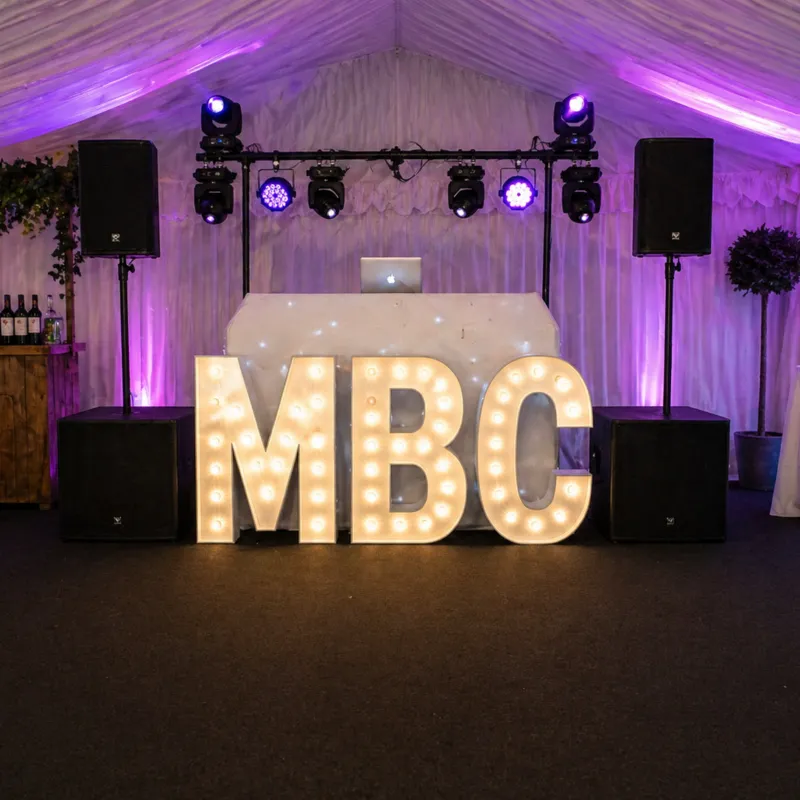 DJ Hire Essex – Marquee DJ Setup with Dancefloor and Lighting DJ hire setup in Essex marquee with speakers, lighting, illuminated letters and dancefloor for party event