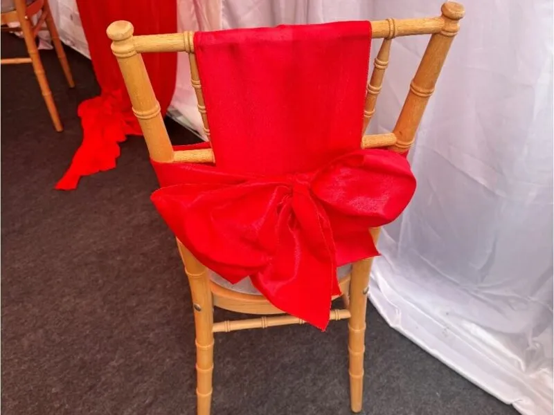Chair Bow Detail – Forest Gate Marquee Setup Chiavari chair with red bow detail inside marquee in Forest Gate during family event setup