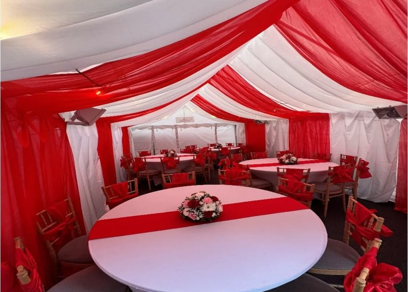 Red Round Table with Centrepiece – Forest Gate Marquee Setup 4m x 8m marquee interior in Forest Gate with red and white draping, round table with centrepiece and Chiavari chairs for family event