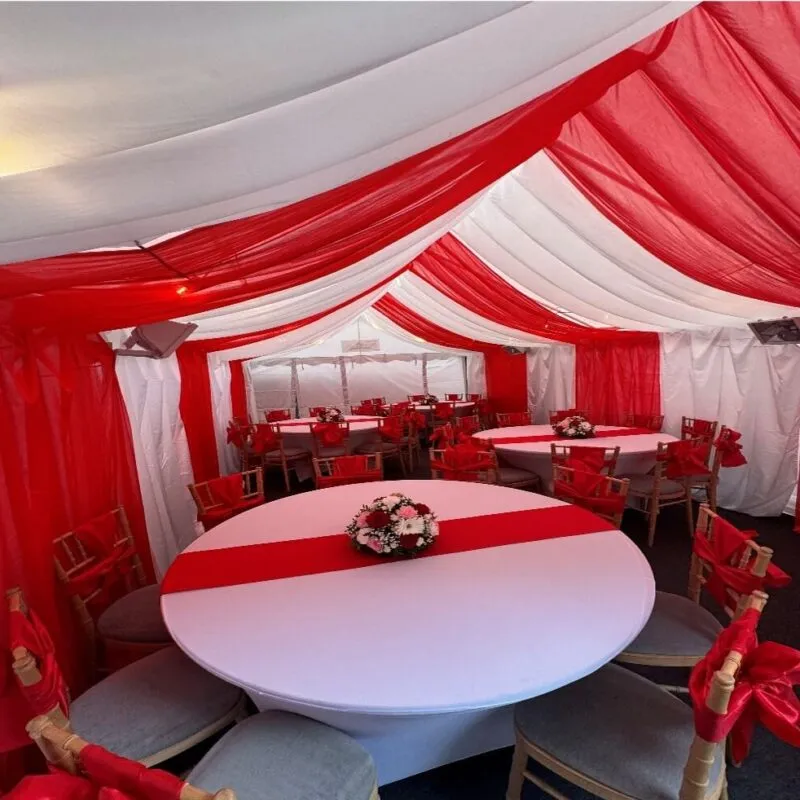 Red Round Table with Centrepiece – Forest Gate Marquee Setup 4m x 8m marquee interior in Forest Gate with red and white draping, round table with centrepiece and Chiavari chairs for family event