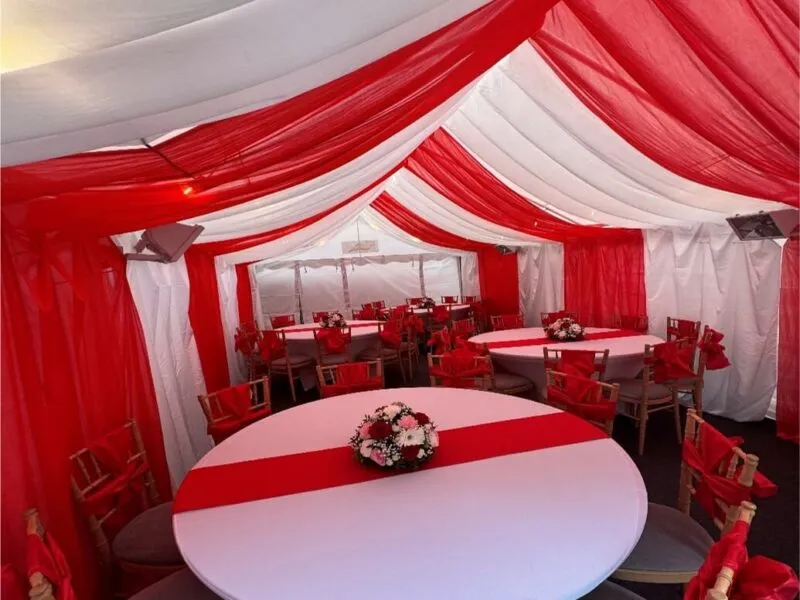 Red Themed Marquee Interior – Forest Gate Event Setup 4m x 8m marquee interior in Forest Gate with red and white draped lining, round table layout and Chiavari chairs for family event
