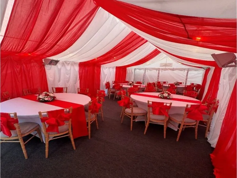 4m x 8m marquee interior in Forest Gate with red and white draping, round table layout and Chiavari chairs for family celebration