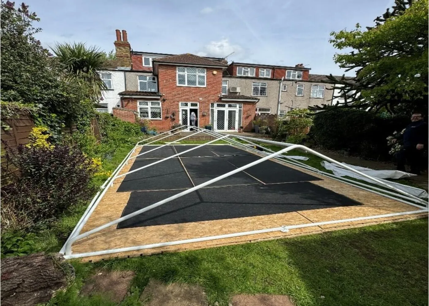 Marquee Frame Preparation – Tilbury Garden Installation Marquee frame laid out on flooring during installation stage in Tilbury garden before assembly