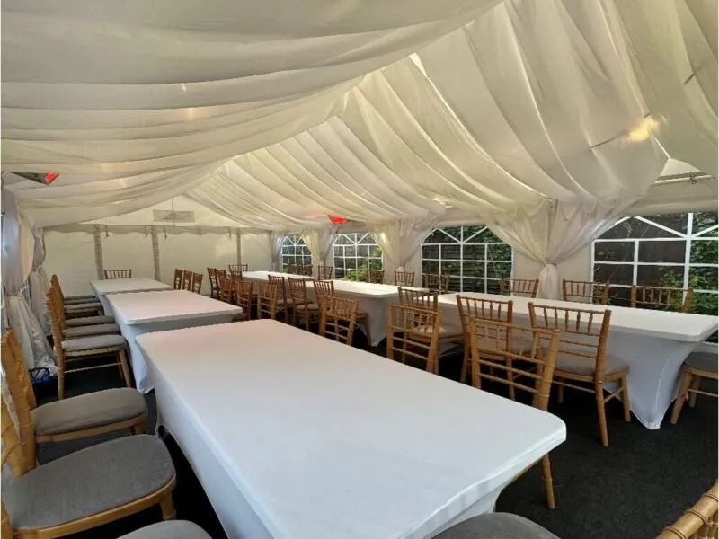 Marquee Interior with Draped Lining – Tilbury Garden Event Marquee interior in Tilbury with white draped lining, long table layout and Chiavari chairs for garden party