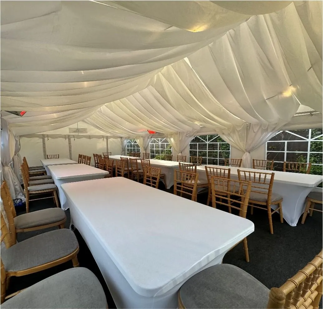 Marquee Interior with Draped Lining – Tilbury Garden Event Marquee interior in Tilbury with white draped lining, long table layout and Chiavari chairs for garden party