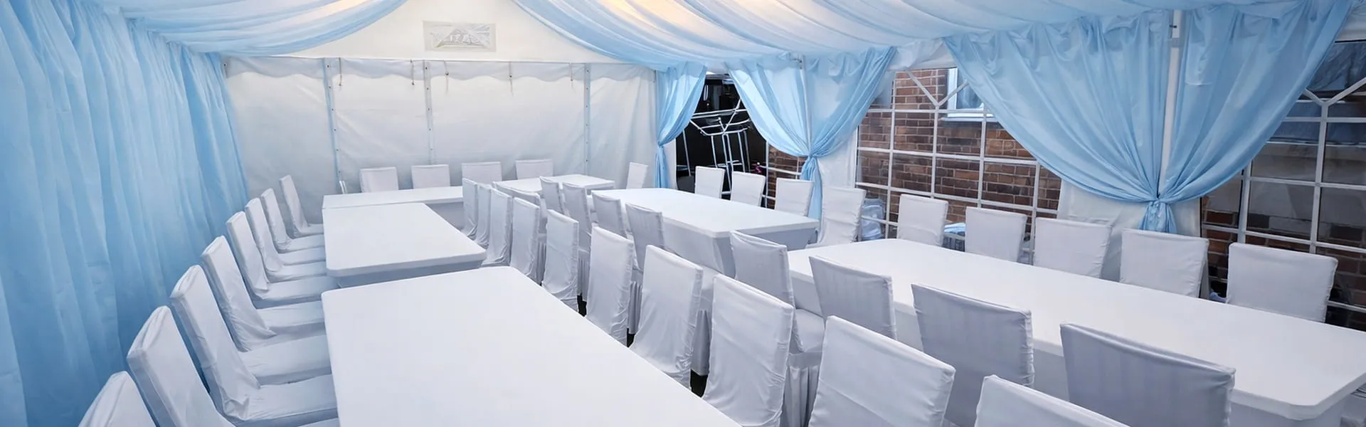 Marquee Event Planning Setup With Blue Draping Marquee interior with long table layout, covered chairs and blue draping for event planning