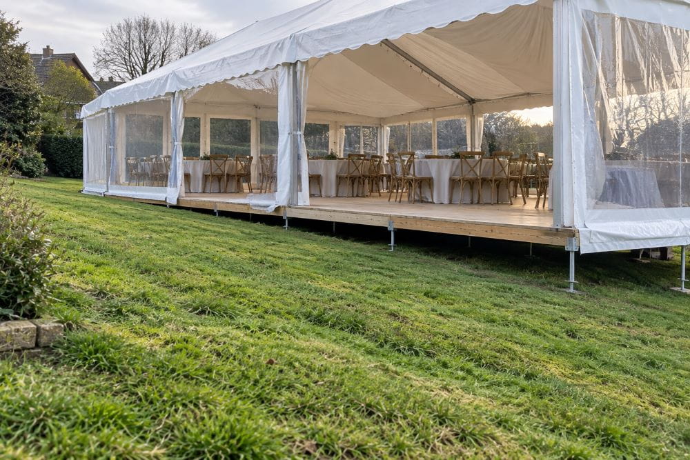 Level marquee flooring supported above a gently sloping grass site