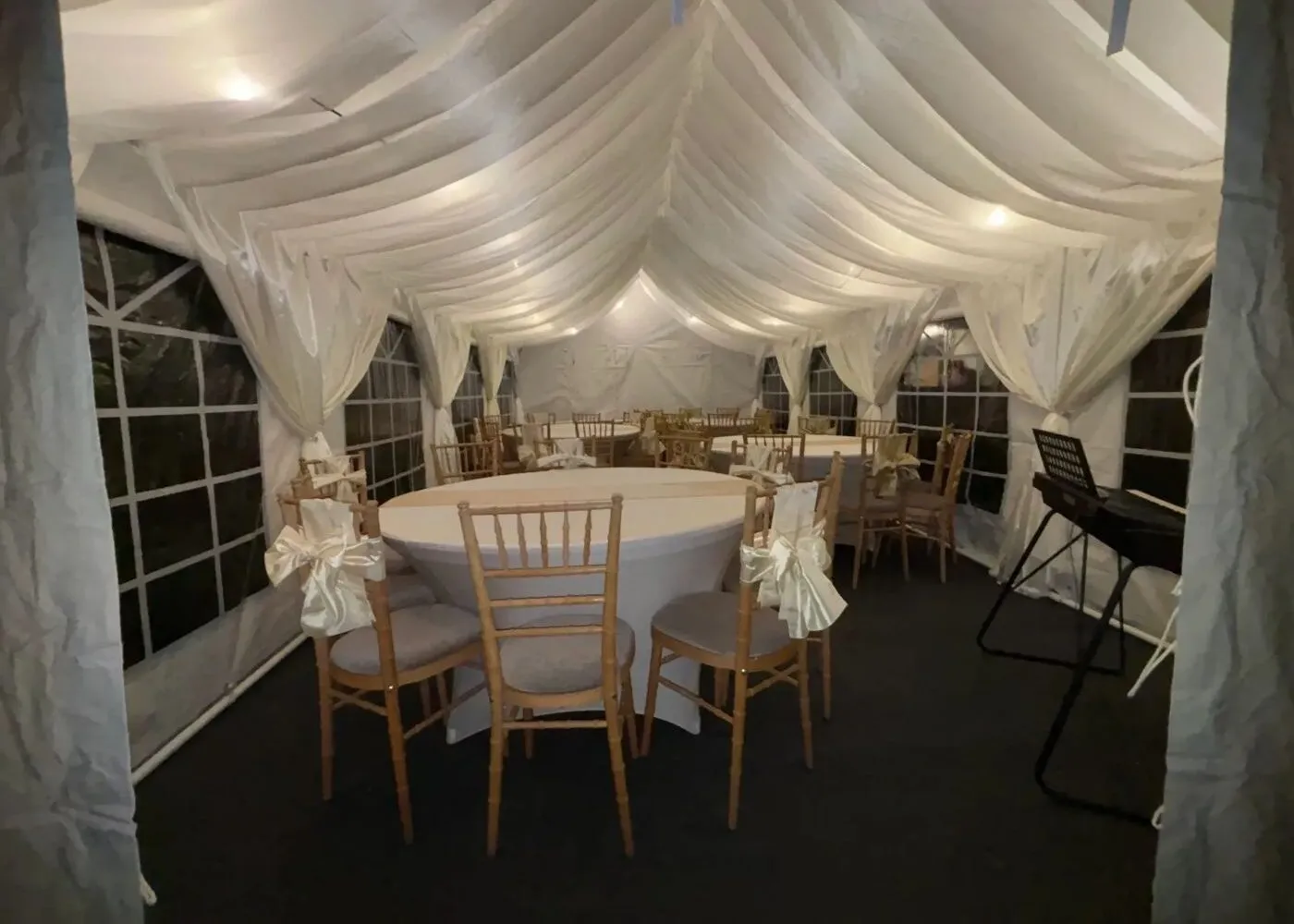 Marquee Hire Essex – Draped Interior Setup Draped marquee interior setup in Essex with round tables and chairs for private event hire