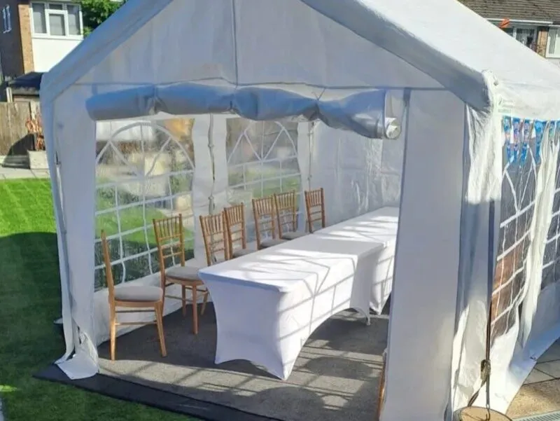 Small marquee hire setup in Essex with table and Chiavari chairs arranged for outdoor event