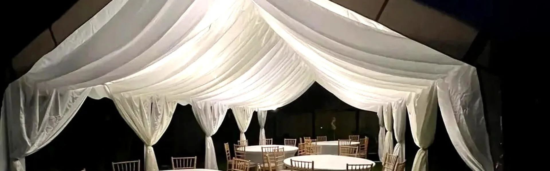 Wedding Marquee Evening Setup With Round Tables Evening wedding marquee setup with round tables, draped ceiling and chairs