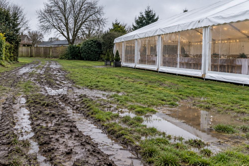 Wet and muddy grass around a marquee site after heavy rainfall