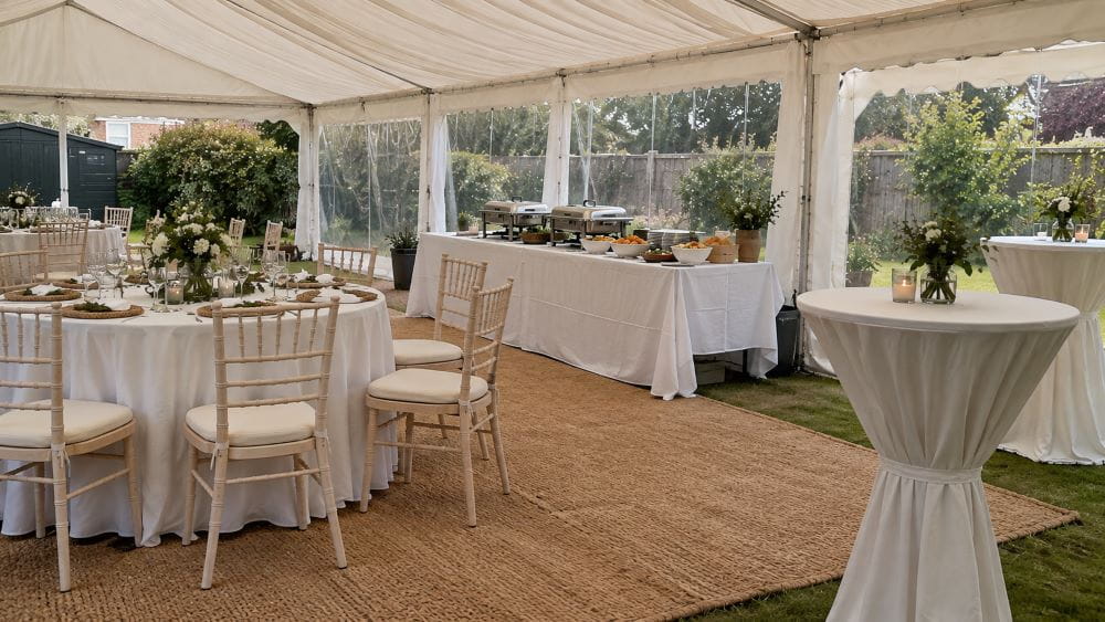 Round dining table, buffet table and cocktail tables inside a garden marquee