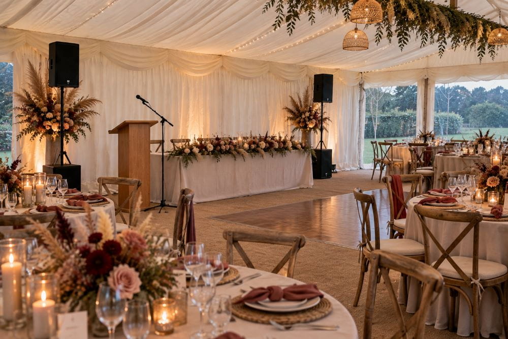 Wedding marquee dining layout with speakers positioned for speeches